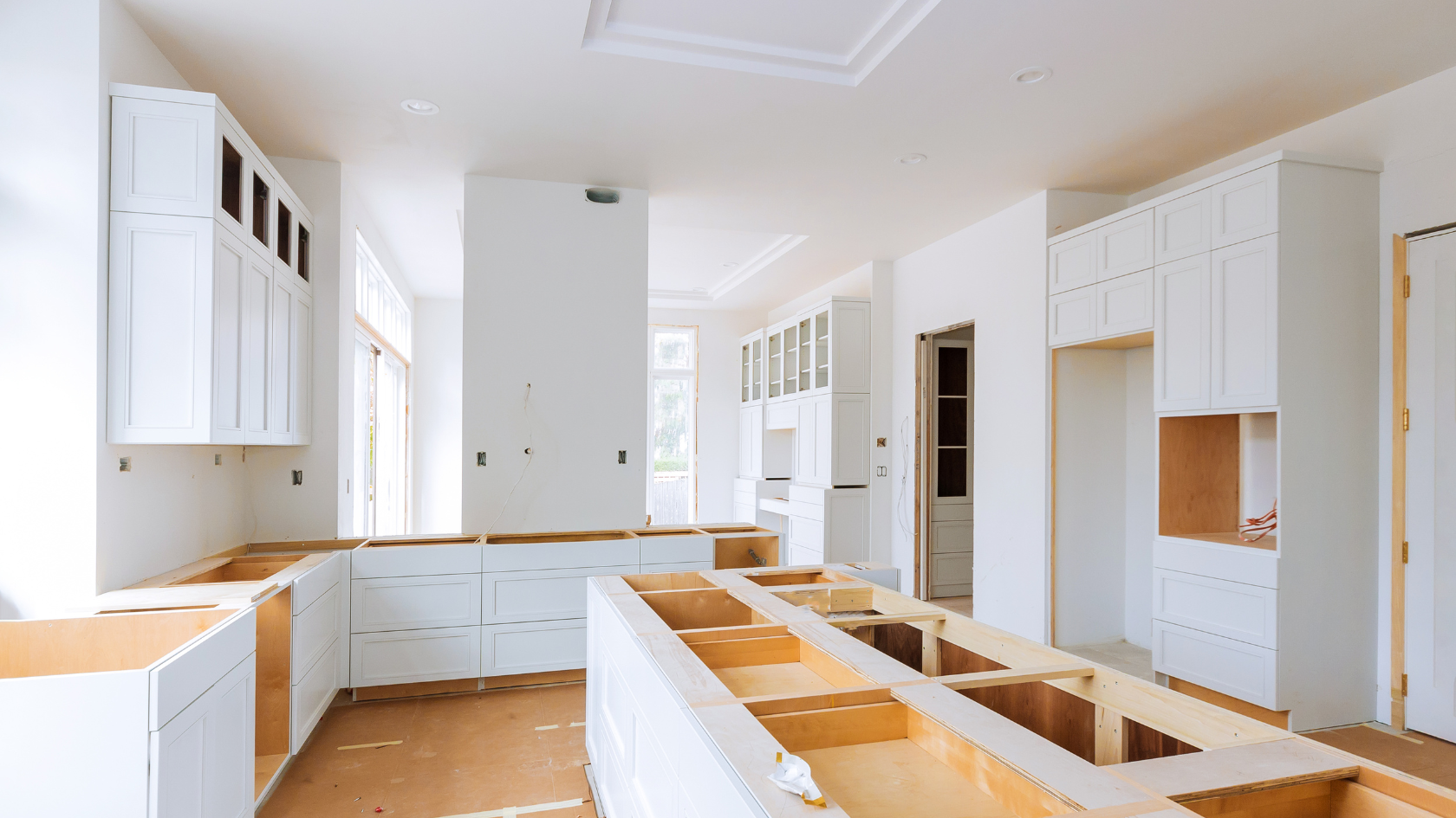 A kitchen being built with white cabinets and drawers